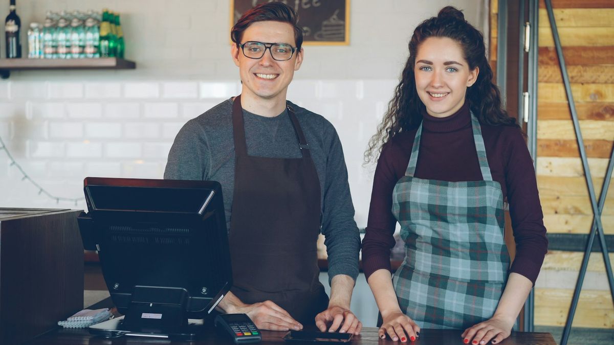 Dos personas sonrientes atendiendo su cafetería